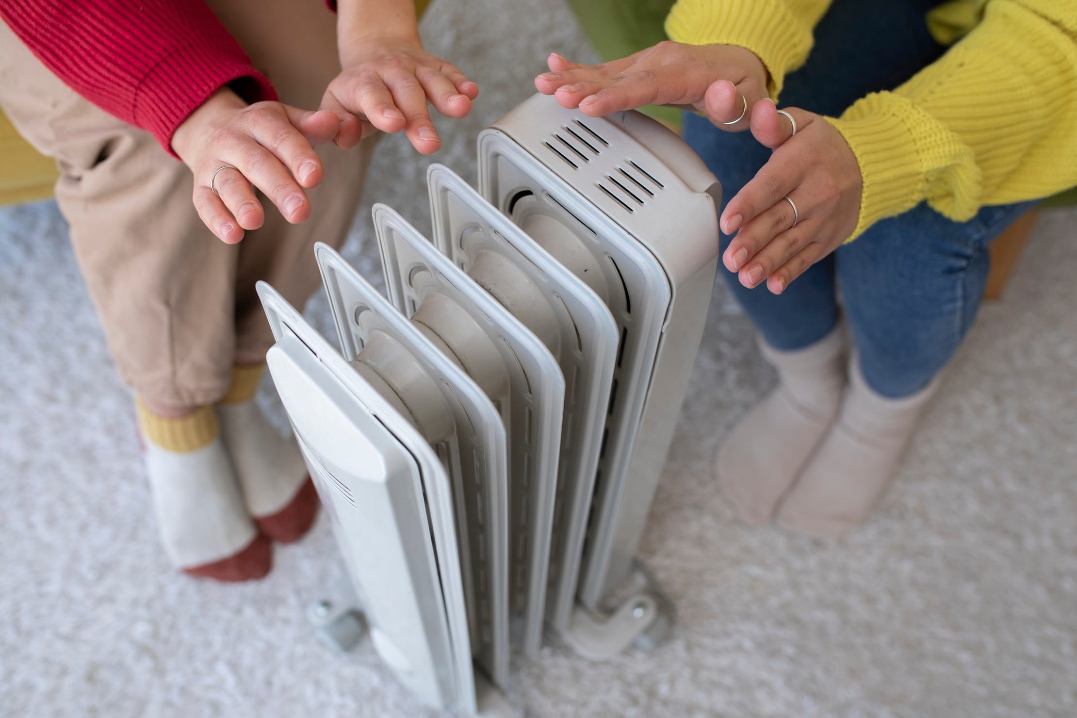 high-angle-people-getting-warm-near-heater